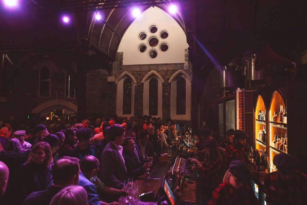 A photo of inside the live music venue, The Church. The picture shows a large crowd in front of a bar.