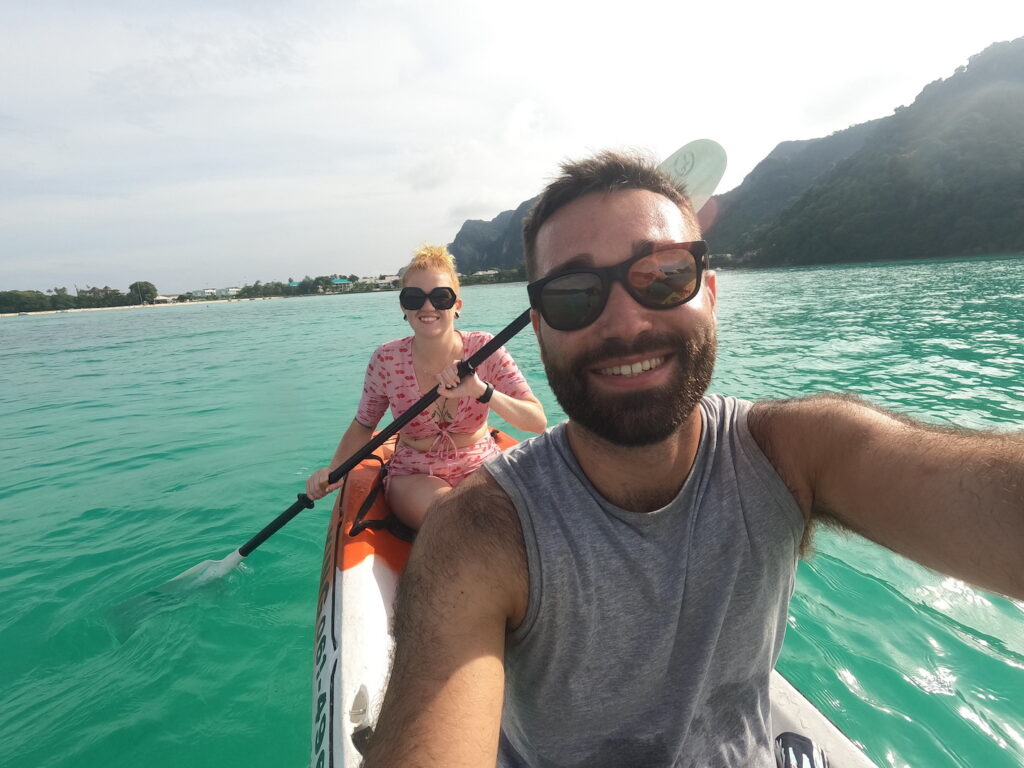 A selfie taken in the waters around Koh Phi Phi (Thailand) of two people in a kayak. The water is green blue, and it is an overcast day.