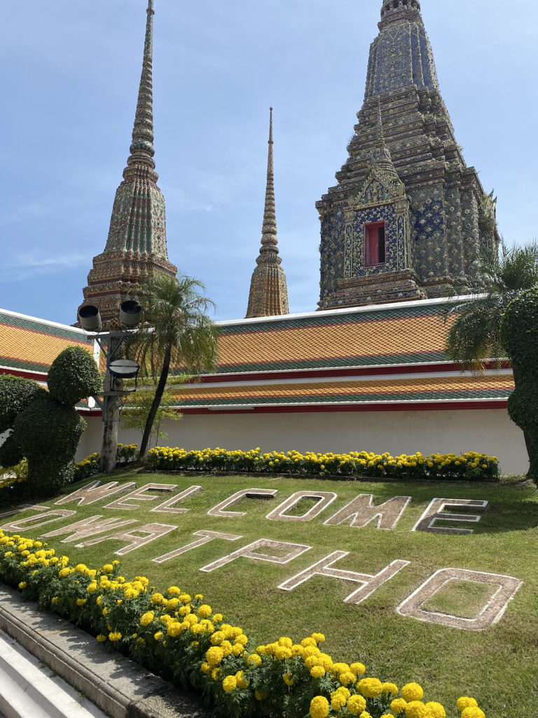 A welcome sign written in the grass: Welcome to Wat Pho. A temple in Bangkok, Thailand.