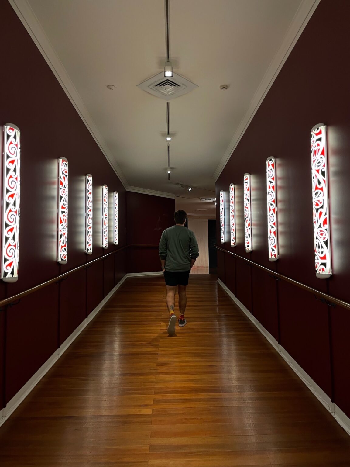 a man waling down a dark corridor with lights following him on either side