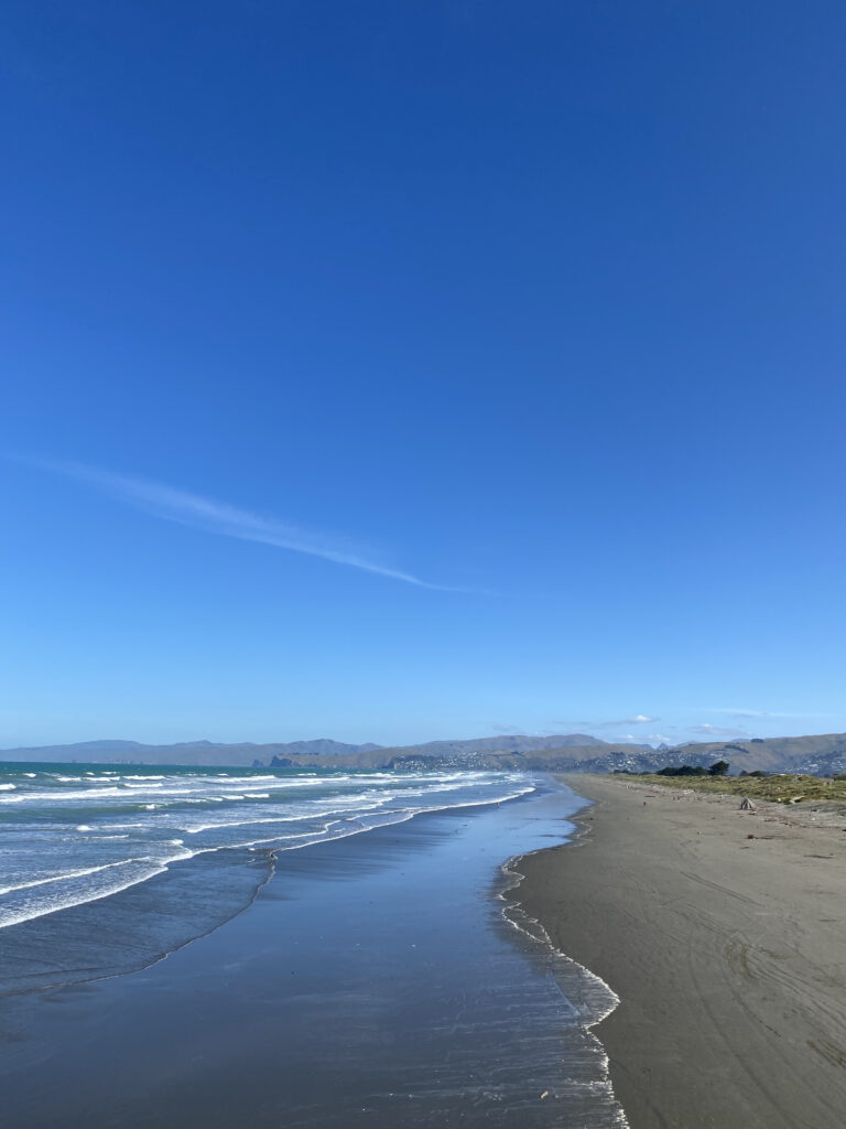 New Brighton beach, New Zealand. In the distance you can see Banks Peninsula with the waves rolling in onto the sandy beach.